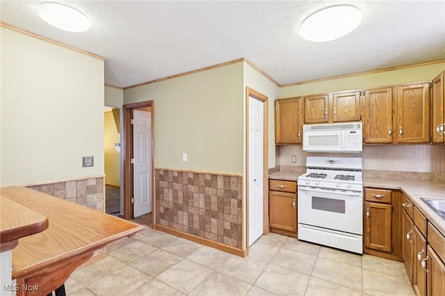 kitchen featuring a textured ceiling, ornamental molding, tile walls, and white appliances