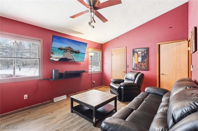 living room featuring ceiling fan, lofted ceiling, and light hardwood / wood-style flooring