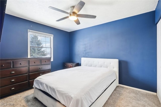 bedroom with ceiling fan, light colored carpet, and a textured ceiling