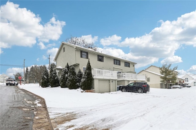 snow covered back of property featuring a garage