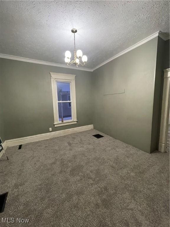 spare room with a textured ceiling, carpet, crown molding, and a notable chandelier