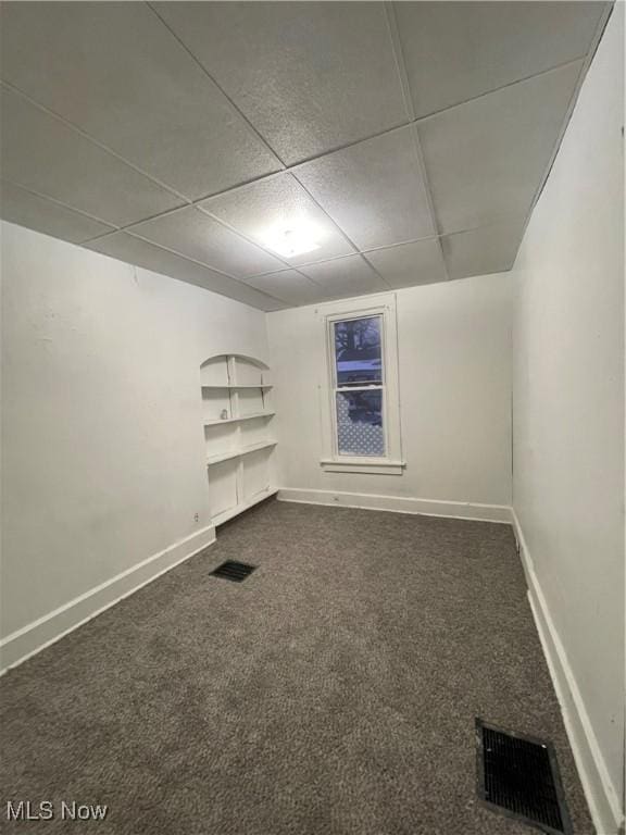 carpeted spare room with built in shelves and a paneled ceiling