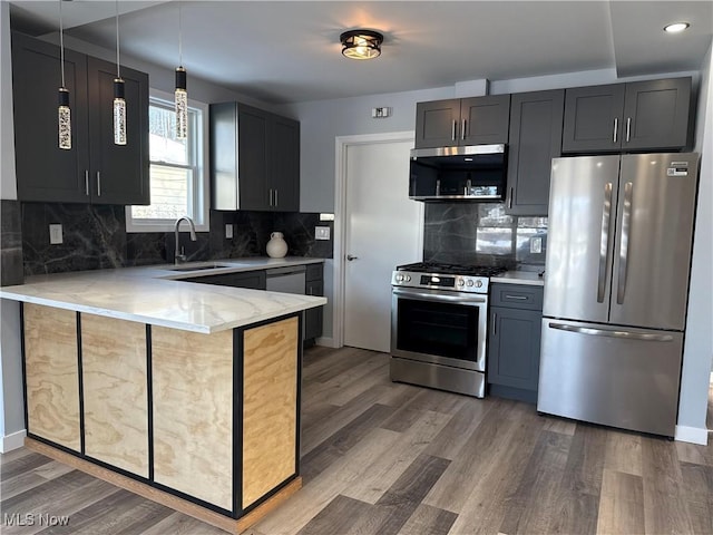 kitchen featuring sink, backsplash, kitchen peninsula, stainless steel appliances, and dark wood-type flooring