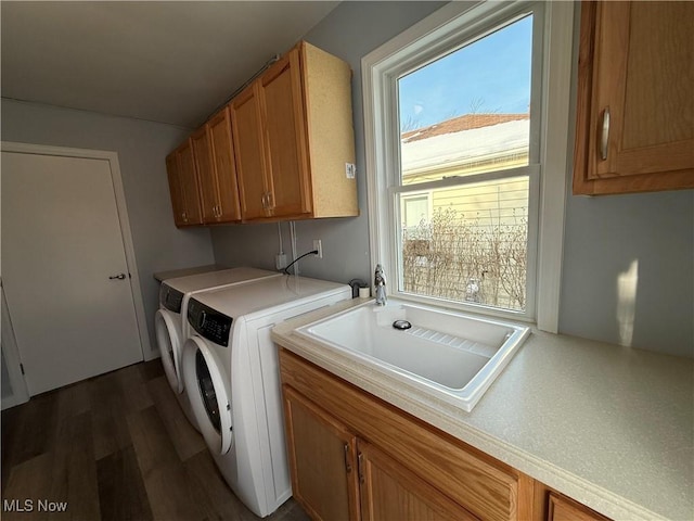 clothes washing area featuring cabinets, washing machine and clothes dryer, dark hardwood / wood-style floors, and sink