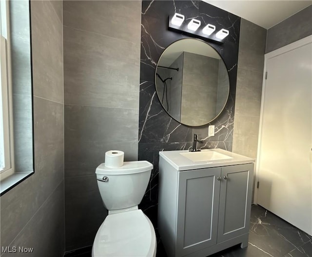 bathroom with tile walls, vanity, and toilet