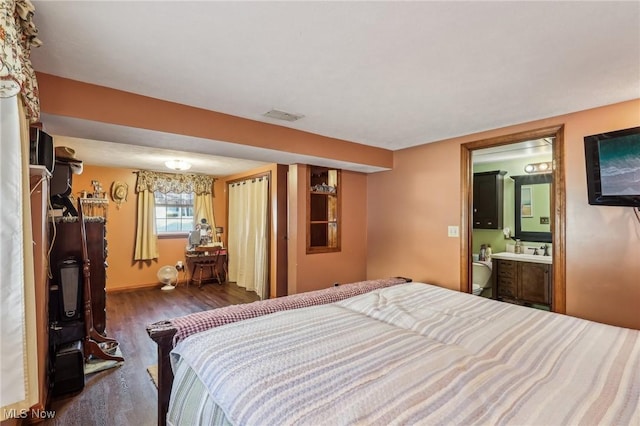 bedroom with ensuite bathroom, dark hardwood / wood-style floors, and sink