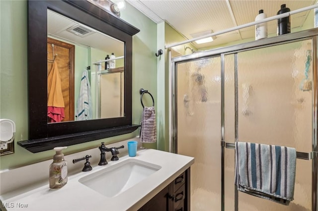 bathroom featuring a shower with shower door and vanity