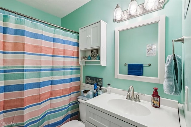 bathroom featuring toilet, vanity, and a shower with curtain