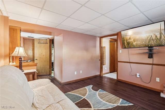 living room featuring a paneled ceiling and dark hardwood / wood-style flooring