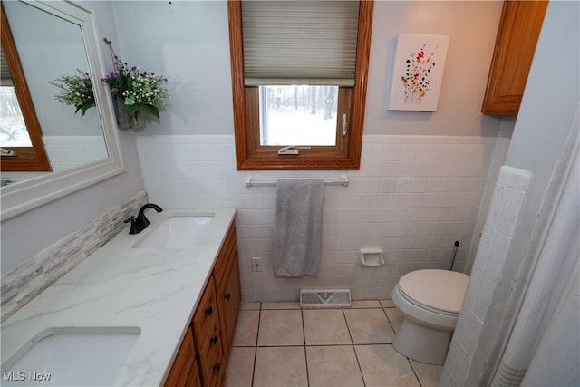 bathroom with toilet, vanity, tile walls, and tile patterned floors