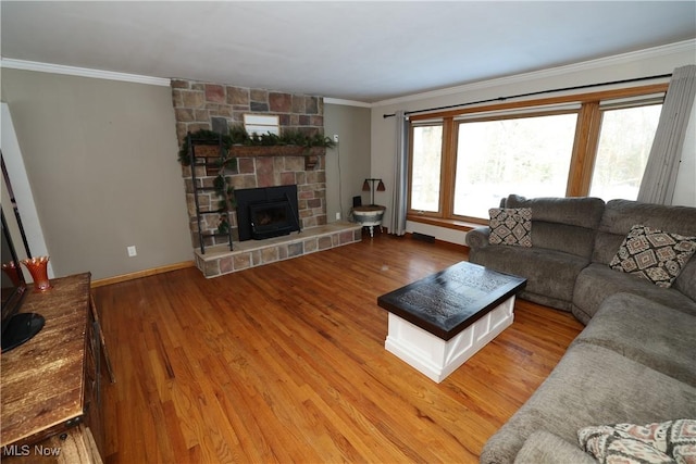 living room featuring ornamental molding, hardwood / wood-style flooring, and a stone fireplace