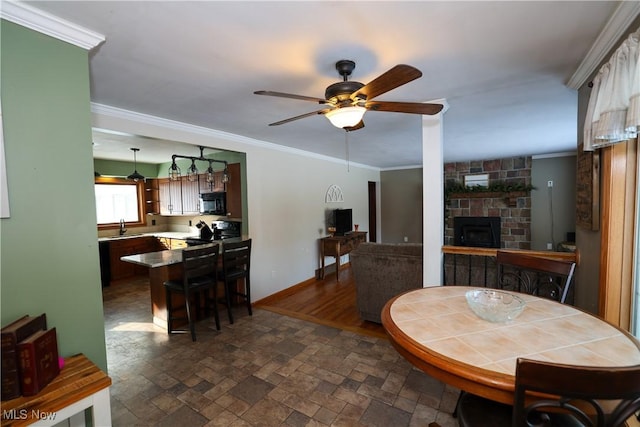 dining room with ceiling fan, a fireplace, sink, and ornamental molding