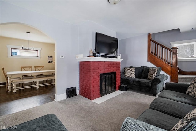 living room featuring carpet, a fireplace, and a notable chandelier