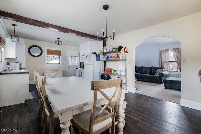 dining area with dark hardwood / wood-style flooring, beam ceiling, and an inviting chandelier