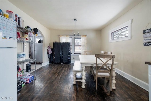 dining space with dark wood-type flooring and an inviting chandelier