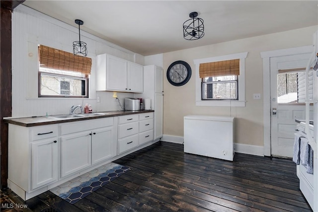 kitchen with fridge, decorative light fixtures, dark wood-type flooring, white cabinets, and sink