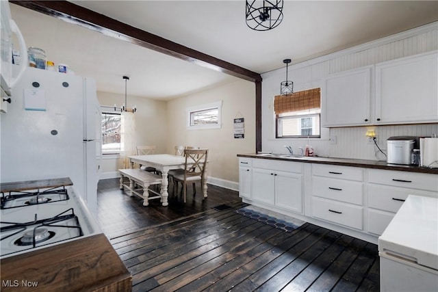 kitchen featuring beamed ceiling, white cabinetry, a healthy amount of sunlight, and decorative light fixtures