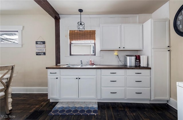 kitchen featuring dark wood-type flooring, sink, white cabinets, and decorative light fixtures