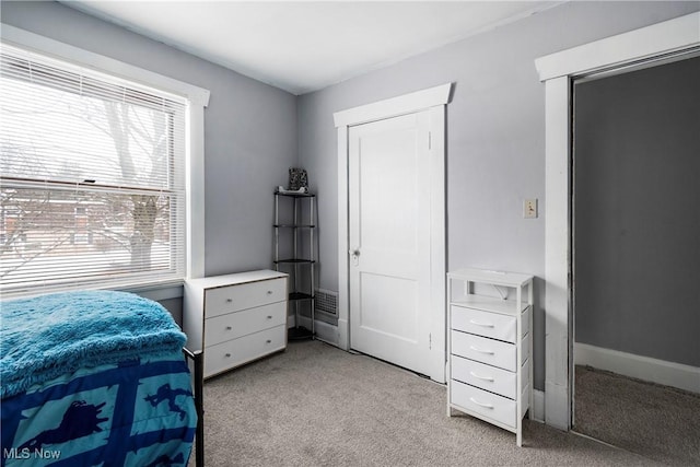 bedroom with light colored carpet, multiple windows, and a closet