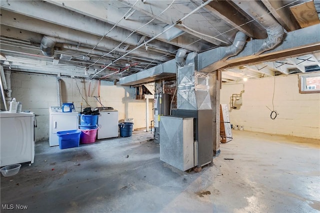 basement featuring heating unit, washer and clothes dryer, fridge, and gas water heater