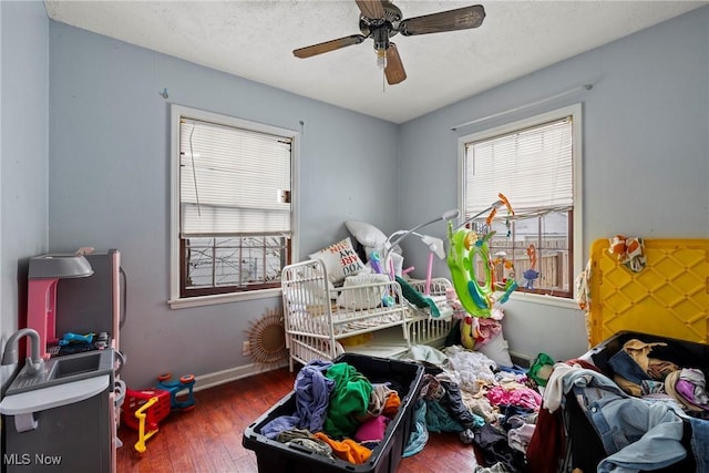 bedroom with ceiling fan, dark wood-type flooring, and a textured ceiling