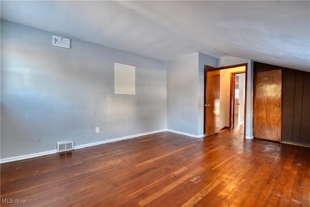 spare room with dark hardwood / wood-style floors and vaulted ceiling