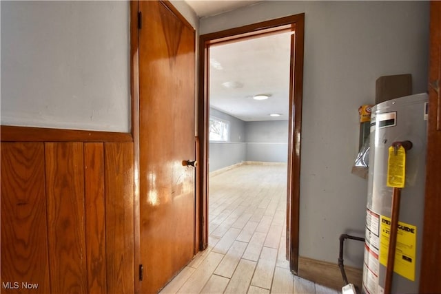 corridor with light wood-type flooring and water heater