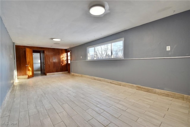 unfurnished room featuring light hardwood / wood-style flooring and wood walls