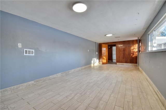 spare room with light hardwood / wood-style flooring and wood walls