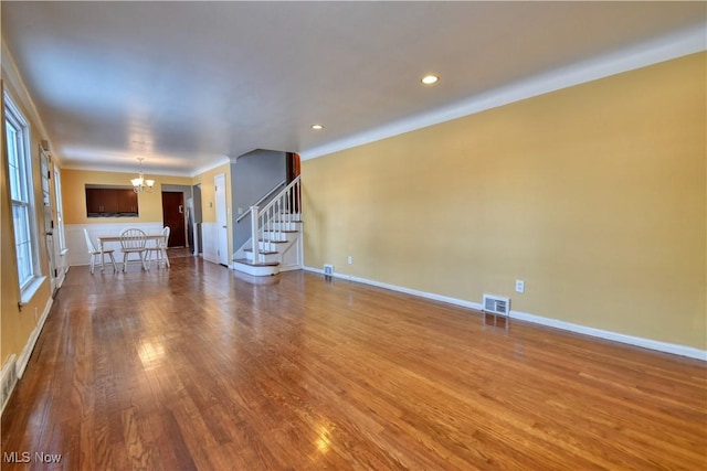 unfurnished living room featuring wood-type flooring and an inviting chandelier