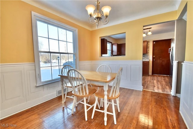 dining space with hardwood / wood-style flooring, plenty of natural light, and a notable chandelier