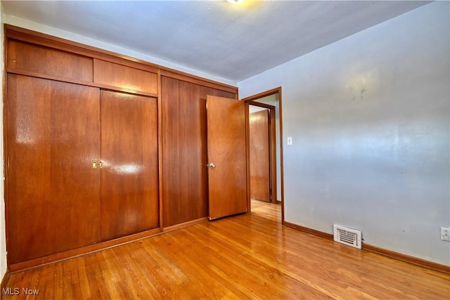 unfurnished bedroom featuring a closet and light wood-type flooring