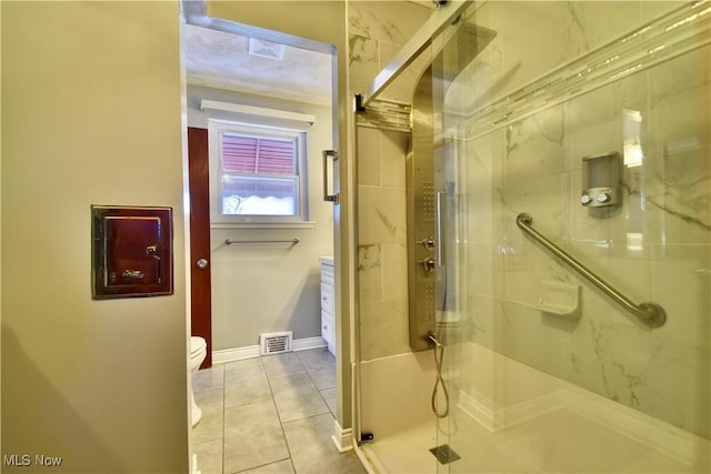 bathroom with tile patterned floors, toilet, and a shower with door