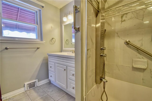 bathroom with tile patterned flooring, a tile shower, and vanity