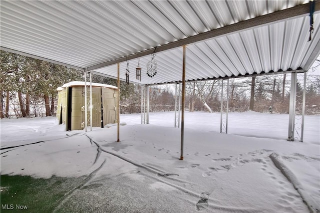 snow covered patio featuring a storage unit