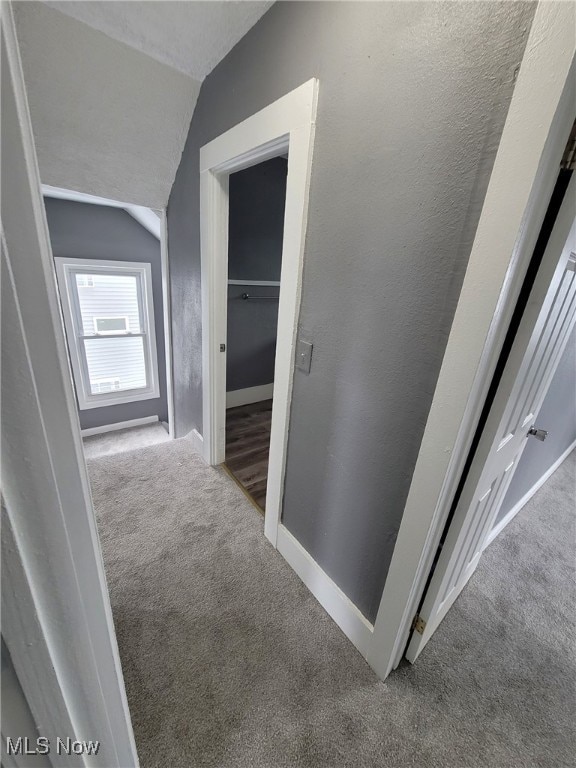 corridor featuring vaulted ceiling, carpet, and a textured ceiling