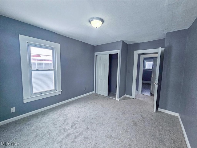 unfurnished bedroom with carpet floors, a textured ceiling, and a closet