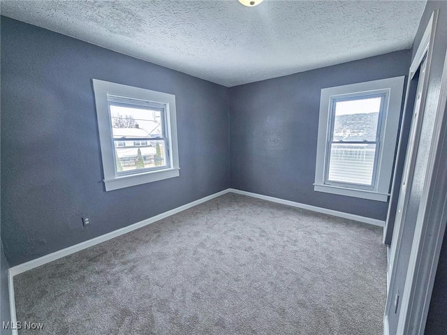 spare room with a textured ceiling and carpet flooring