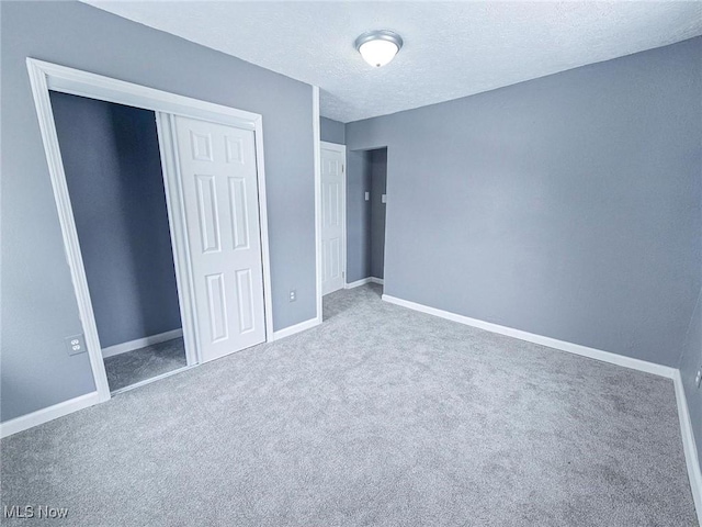 unfurnished bedroom featuring a textured ceiling, a closet, and carpet flooring