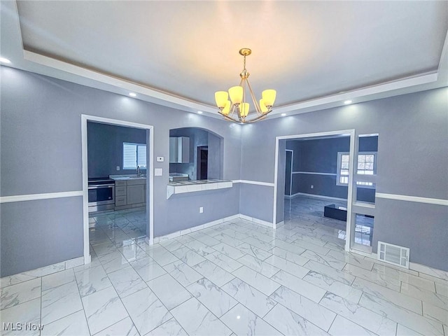 spare room featuring an inviting chandelier, a raised ceiling, and sink