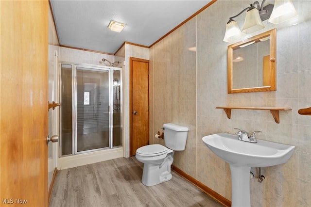 bathroom with toilet, crown molding, a shower with shower door, and wood-type flooring