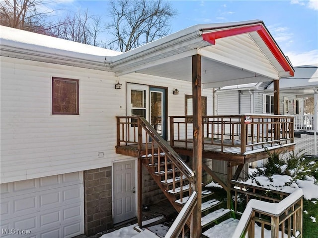 snow covered property entrance with a garage