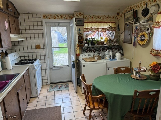 kitchen with plenty of natural light, light tile patterned floors, white gas stove, and ventilation hood