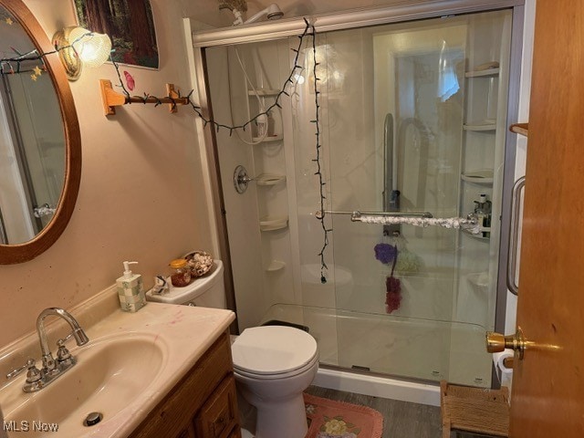 full bathroom with toilet, vanity, wood finished floors, and a stall shower