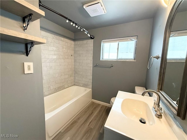 full bathroom featuring hardwood / wood-style flooring, tiled shower / bath, vanity, and toilet