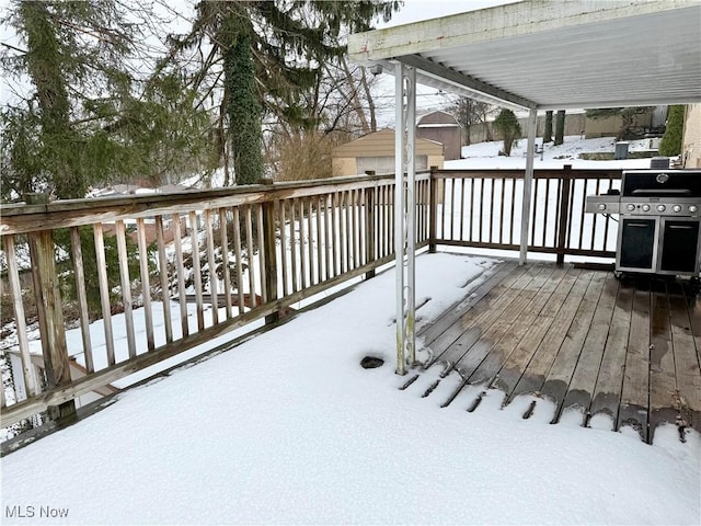 snow covered deck featuring grilling area and a storage unit