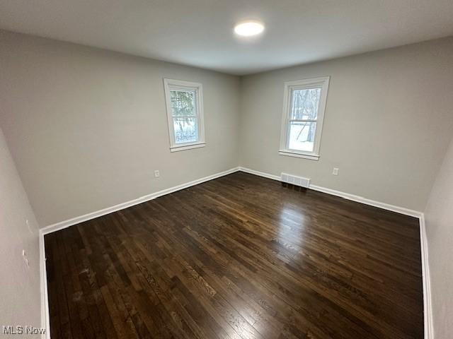 unfurnished room with dark hardwood / wood-style flooring