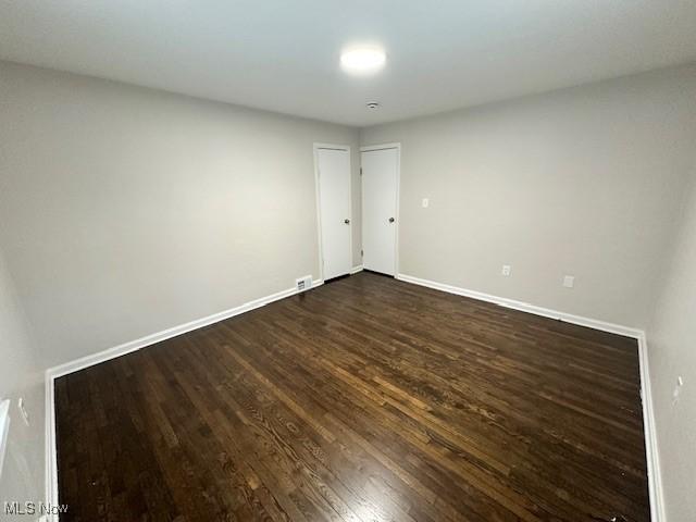 unfurnished room with dark wood-type flooring