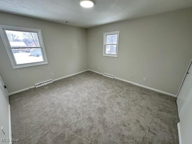 unfurnished room featuring carpet floors and a baseboard radiator