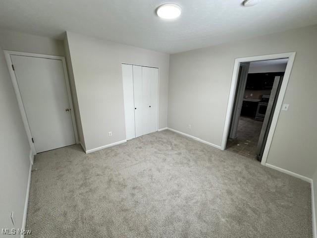 unfurnished bedroom with a closet and light carpet